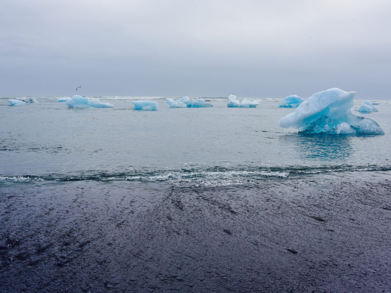 blue icebergs black sand