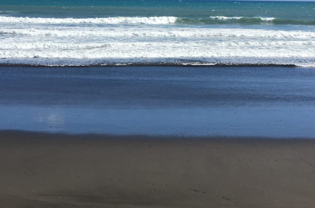 black sand blue water white waves