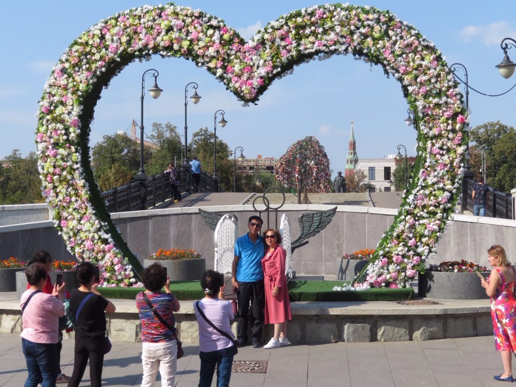 couple taking a photo in front of rose heart