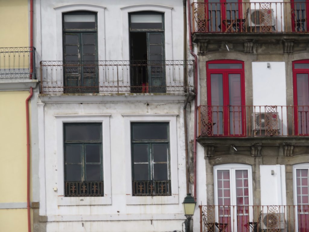 building with red window frames next to building with green window frames